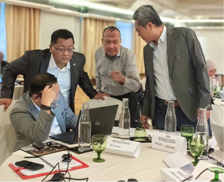 Professionals collaborating around a laptop during practical GHG learning